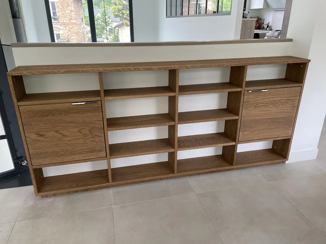 Buffet bas en bois avec niches et portes, installé sous une verrière