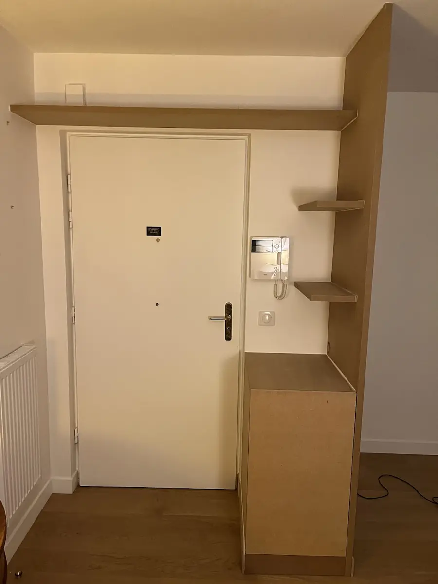 Meuble d’entrée sur mesure avec étagères, à côté d’une porte d’appartement