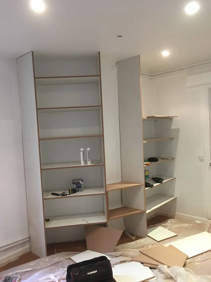 Bibliothèque blanche à étagères montée dans une pièce en travaux
