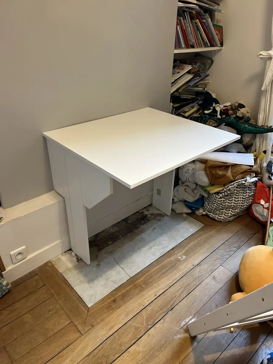 Bureau blanc monté dans une chambre, contre le mur, sur parquet