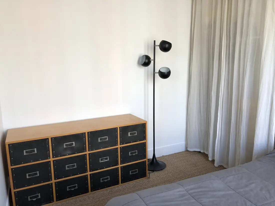 Commode à tiroirs montée dans une chambre, près d’un lampadaire