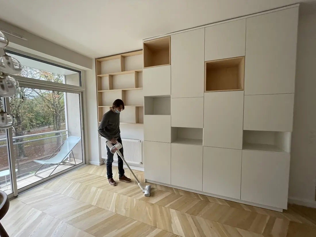 Rangements blancs sur mesure avec niches en bois, posés dans un séjour lumineux