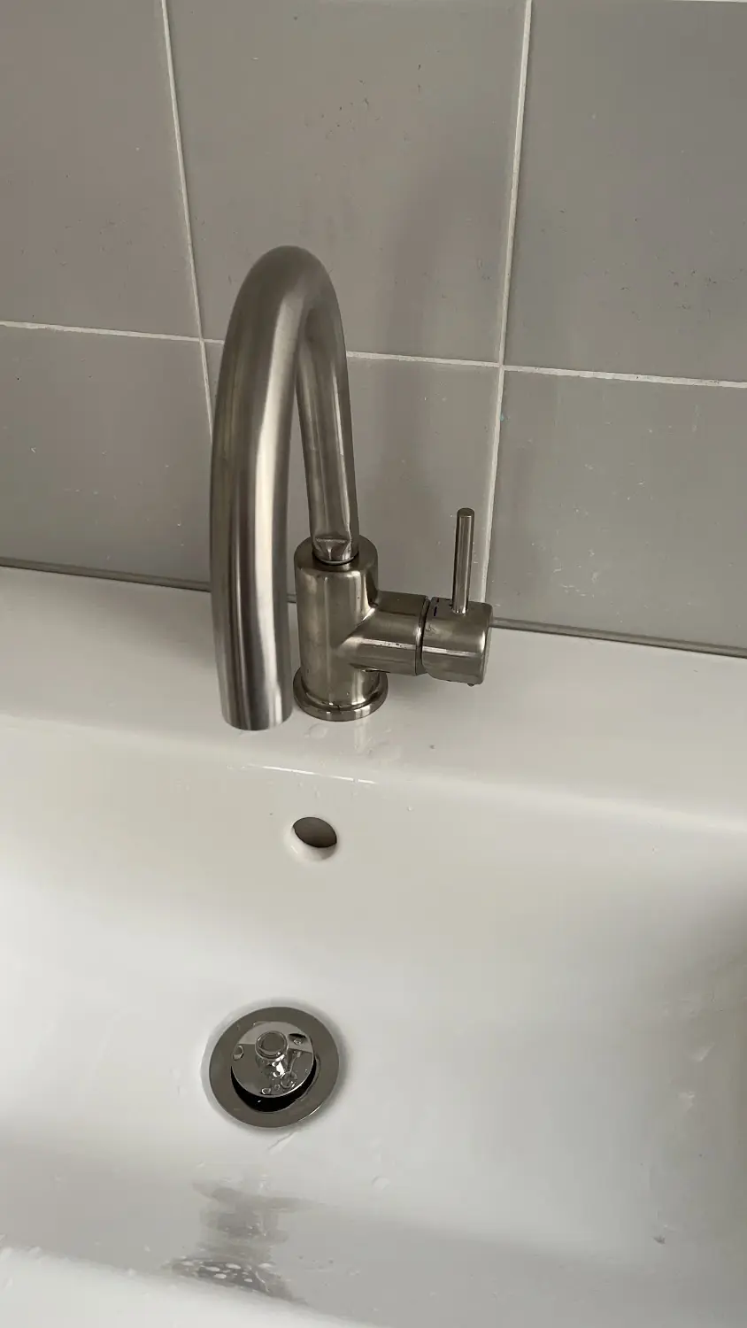 Robinet de lavabo en inox posé sur une vasque blanche