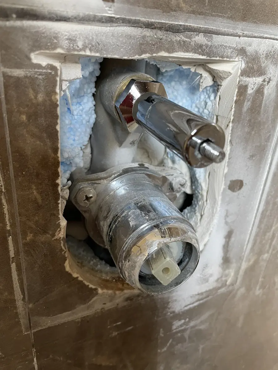 Robinetterie encastrée mise à nu dans un mur ouvert avant réparation